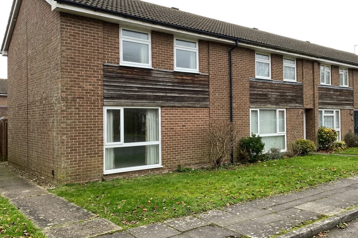 White uPVC windows on the upper floor of a 1970s brick end-of-terrace house with a band of timber cladding